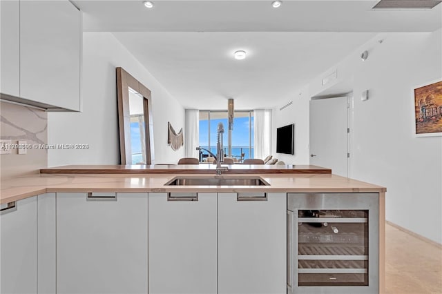 15701 Collins Ave Unit 703, Sunny Isles Beach, FL 33160 - kitchen featuring wine cooler, a sink, white cabinets, open floor plan, and light countertops