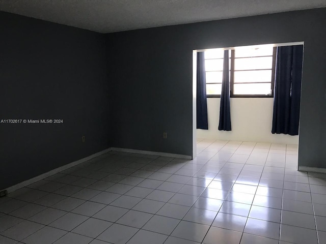 tiled empty room featuring a textured ceiling