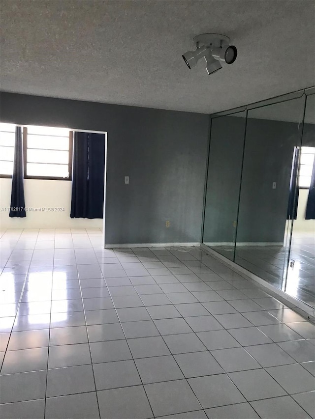 empty room with light tile patterned floors and a textured ceiling