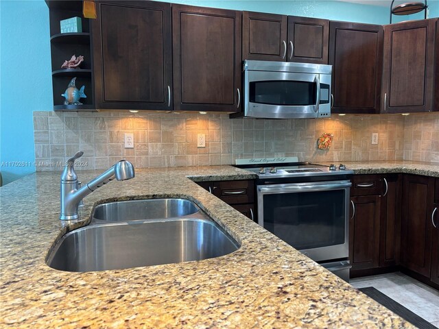 kitchen featuring backsplash, light stone countertops, sink, and appliances with stainless steel finishes