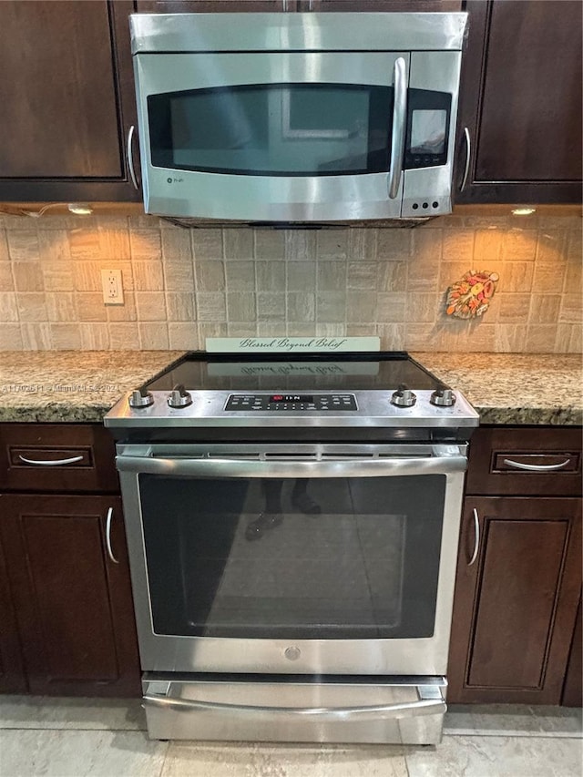 kitchen featuring dark brown cabinets, decorative backsplash, light stone countertops, and appliances with stainless steel finishes