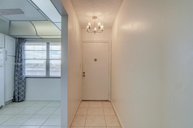 entryway with light tile patterned floors, a textured ceiling, and a notable chandelier