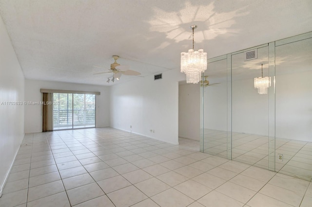 tiled spare room featuring a textured ceiling and ceiling fan with notable chandelier