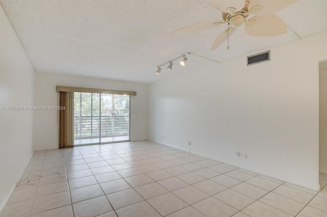 spare room featuring ceiling fan, light tile patterned floors, and a textured ceiling