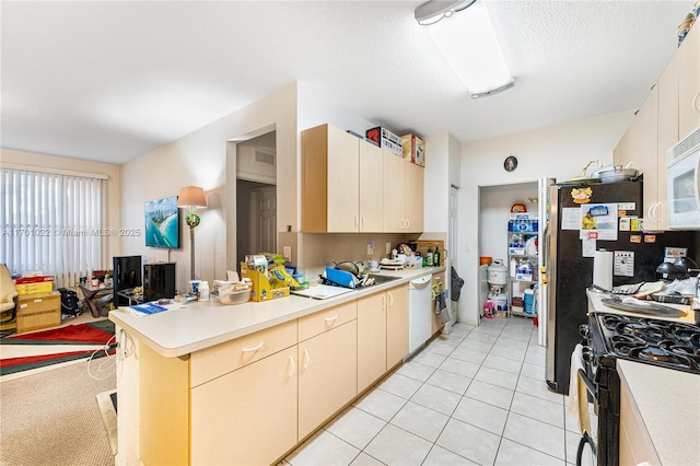 kitchen featuring sink, light tile patterned floors, white appliances, a textured ceiling, and kitchen peninsula