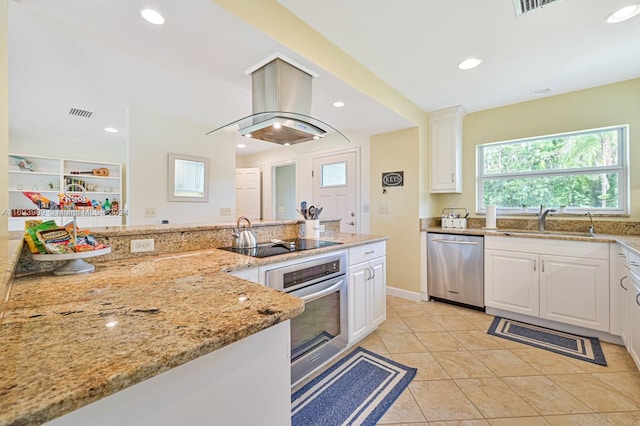 kitchen with light stone countertops, stainless steel appliances, island range hood, sink, and white cabinetry