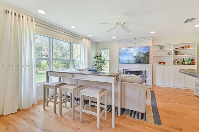 dining area featuring a fireplace, light hardwood / wood-style floors, and ceiling fan