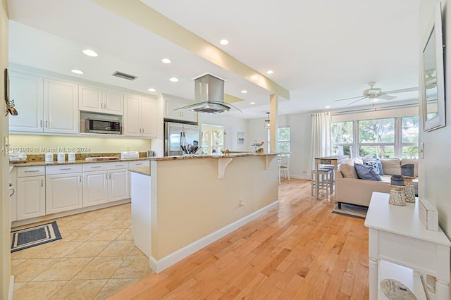 kitchen featuring island range hood, white cabinets, ceiling fan, appliances with stainless steel finishes, and light hardwood / wood-style floors