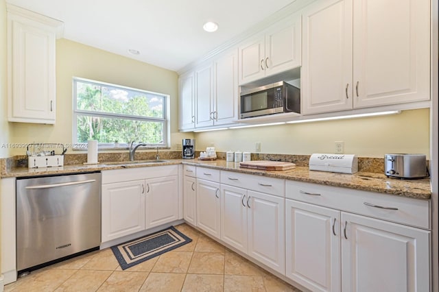 kitchen with light stone countertops, white cabinetry, sink, and appliances with stainless steel finishes