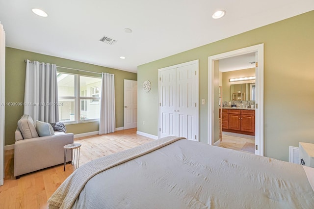 bedroom featuring connected bathroom and light hardwood / wood-style flooring