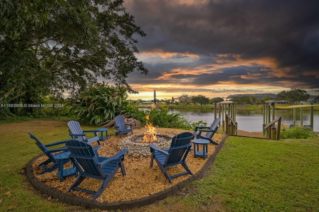 yard at dusk featuring a water view and a fire pit