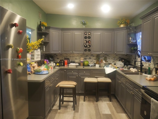 kitchen with decorative backsplash, appliances with stainless steel finishes, light hardwood / wood-style floors, and sink