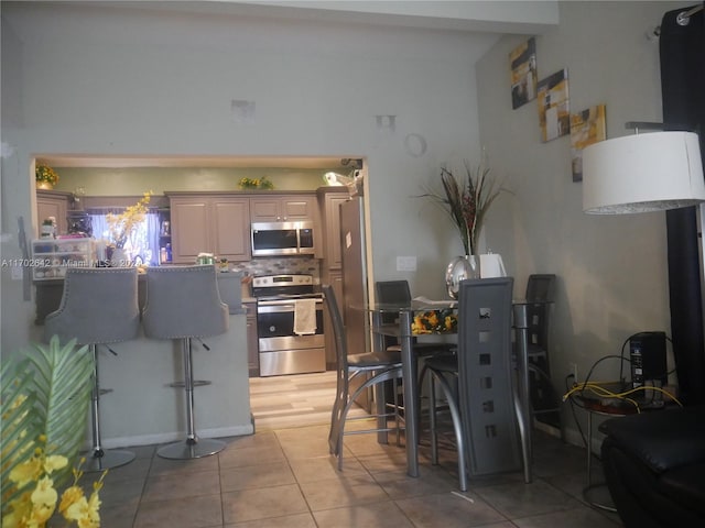 kitchen with a kitchen bar, light tile patterned flooring, and appliances with stainless steel finishes