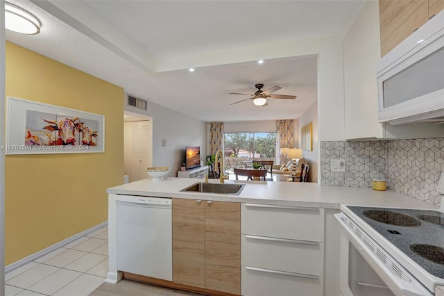 kitchen featuring kitchen peninsula, backsplash, white appliances, sink, and white cabinetry