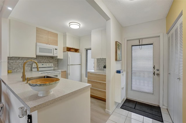 kitchen with light brown cabinets, white appliances, tasteful backsplash, light tile patterned flooring, and kitchen peninsula