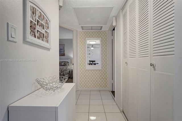 corridor featuring a textured ceiling and light tile patterned flooring