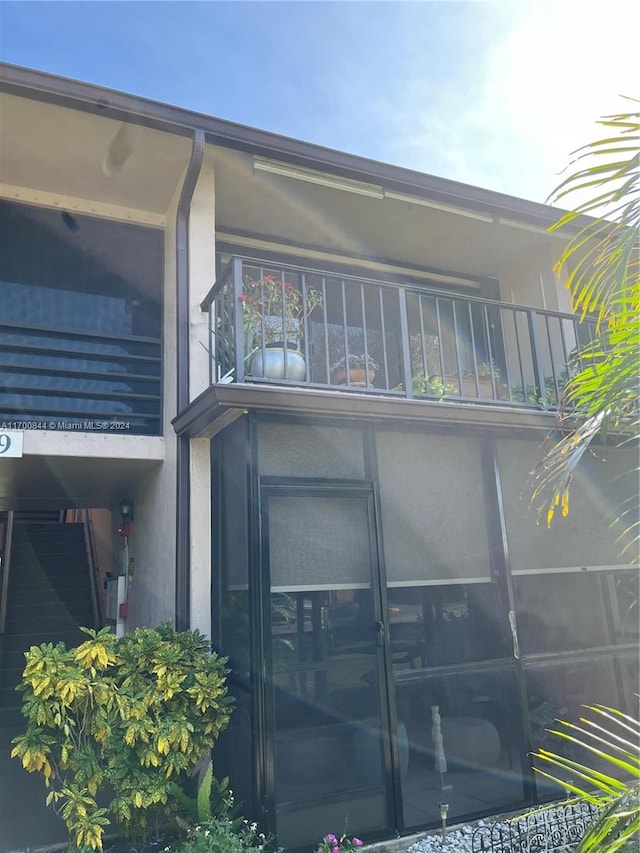 back of property featuring a sunroom and a balcony