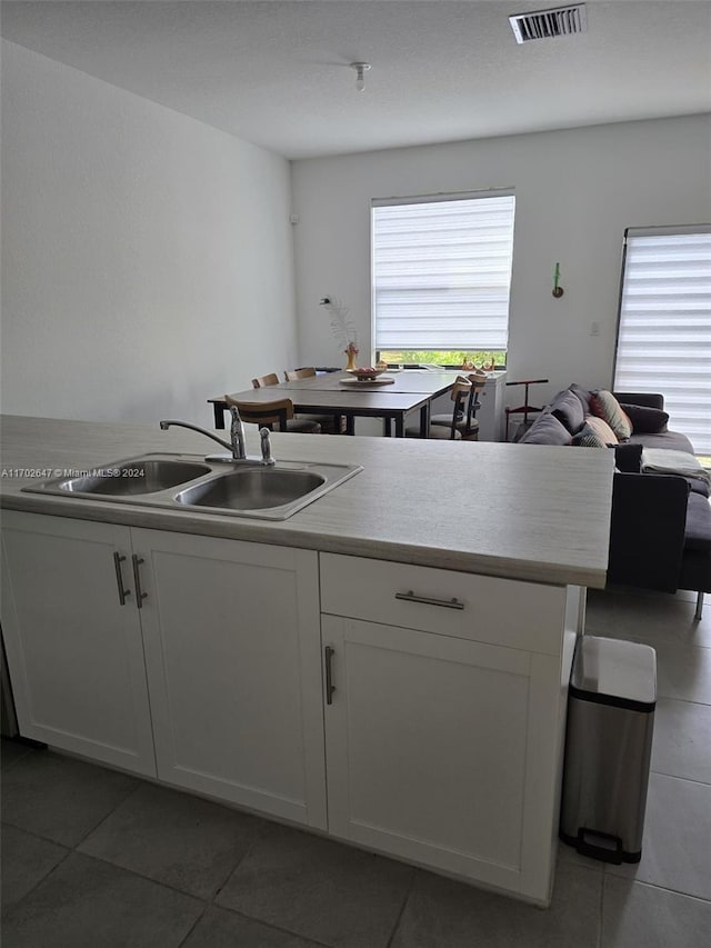 kitchen with white cabinets, sink, a wealth of natural light, and dark tile patterned flooring