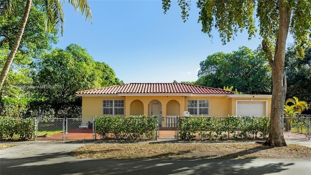 mediterranean / spanish-style house featuring a gate, stucco siding, a garage, a fenced front yard, and a tile roof