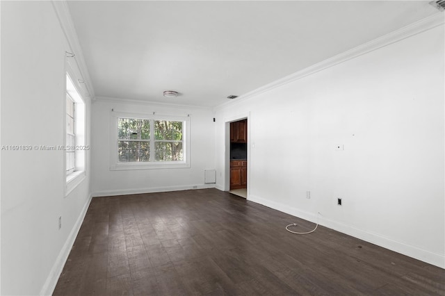 spare room with visible vents, baseboards, ornamental molding, and dark wood finished floors