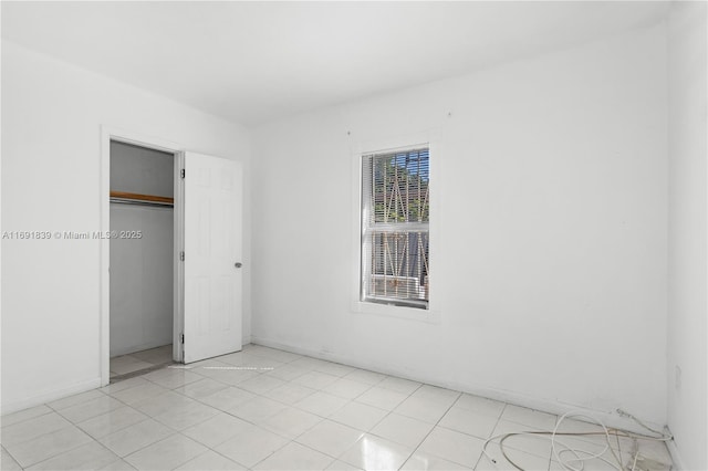 unfurnished bedroom featuring light tile patterned flooring, baseboards, and a closet