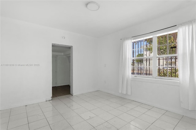 spare room with light tile patterned flooring and baseboards