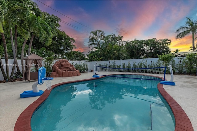 pool at dusk featuring a patio