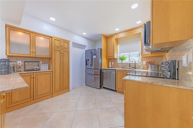 kitchen featuring light tile patterned flooring, light stone countertops, sink, and appliances with stainless steel finishes