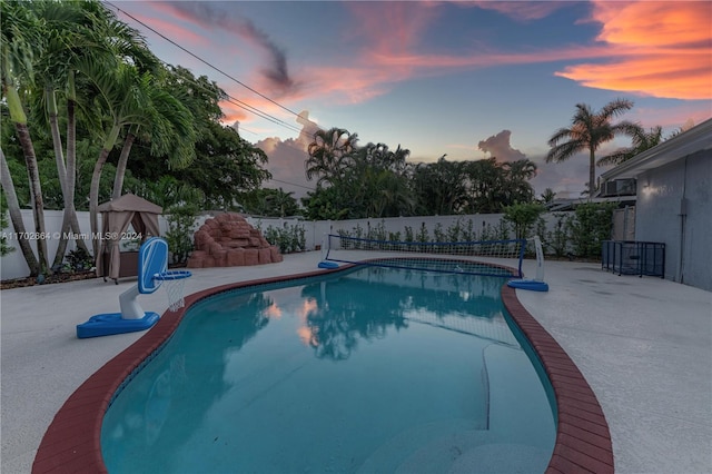 pool at dusk featuring a patio