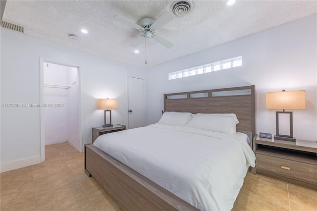 tiled bedroom with a textured ceiling, a closet, a spacious closet, and ceiling fan