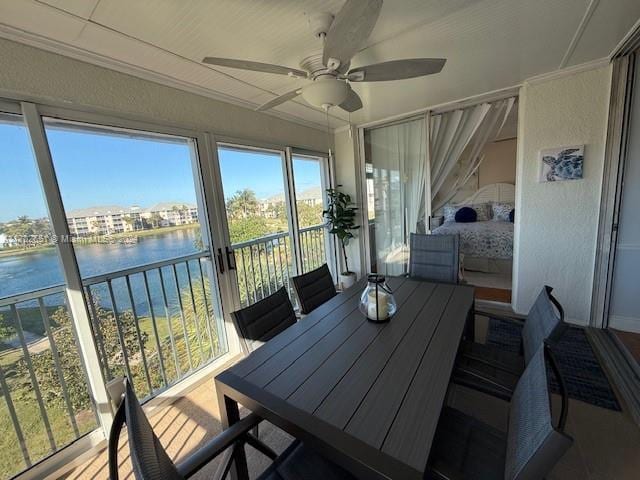 sunroom / solarium featuring a water view and ceiling fan