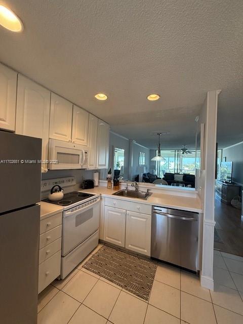 kitchen with sink, white appliances, light tile patterned floors, and white cabinets