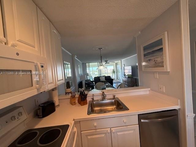 kitchen with white appliances, sink, a textured ceiling, and white cabinets