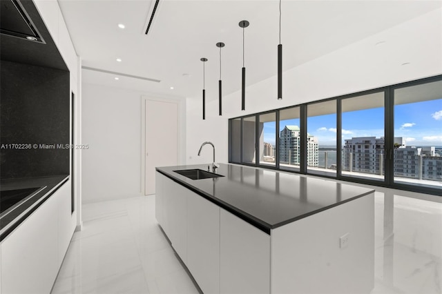 kitchen featuring white cabinets, a view of city, pendant lighting, and a sink