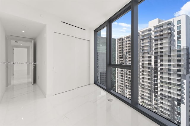 unfurnished room featuring marble finish floor, a city view, and floor to ceiling windows