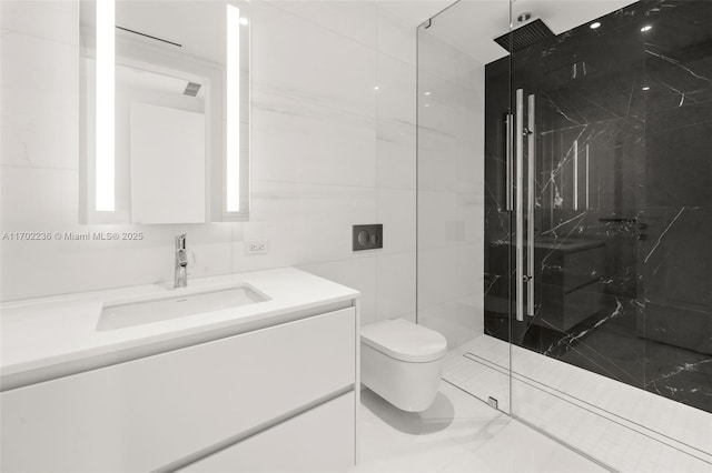 bathroom featuring toilet, a marble finish shower, tile walls, and vanity