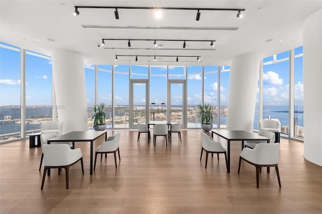 dining room with a water view, a wall of windows, and wood finished floors