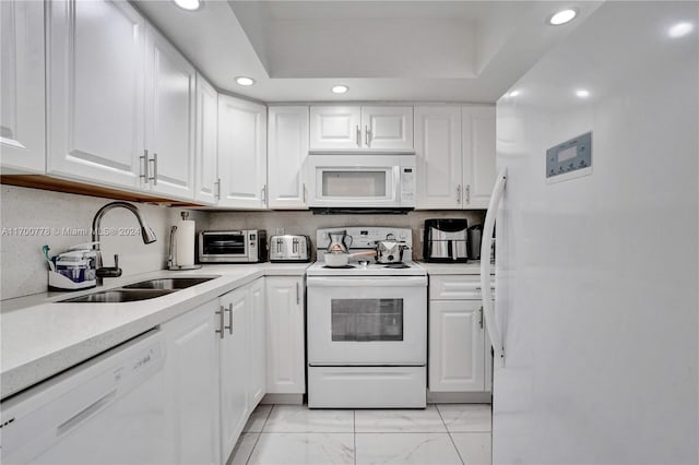 kitchen with backsplash, white cabinetry, sink, and white appliances