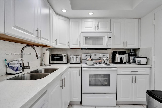 kitchen featuring sink, white cabinets, and white appliances