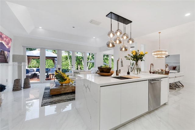 kitchen with sink, an island with sink, pendant lighting, light stone countertops, and white cabinets