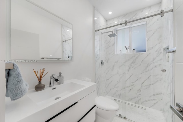 bathroom featuring vanity, a shower with shower door, and toilet