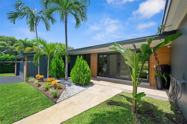 exterior space with a lawn, a garage, and french doors