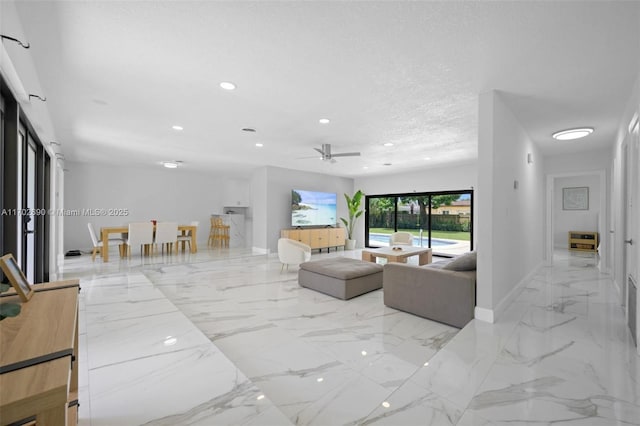 living room featuring ceiling fan and a textured ceiling