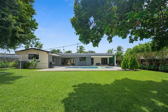 back of property featuring a yard, a patio, and a fenced in pool