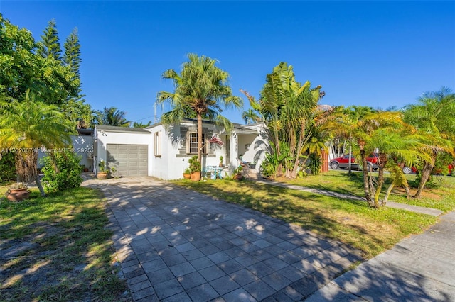 view of front of property featuring a garage, a front yard, decorative driveway, and stucco siding