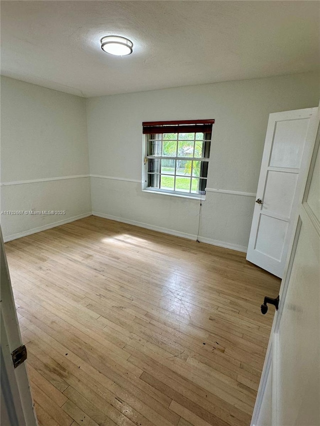 spare room with wood-type flooring, a textured ceiling, and baseboards