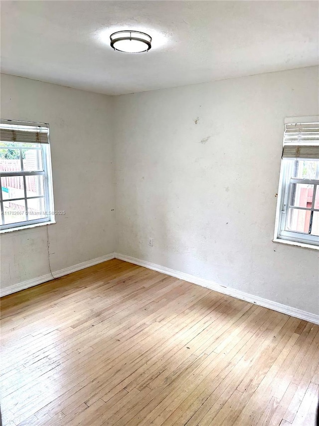 unfurnished room with wood-type flooring, a wealth of natural light, and baseboards