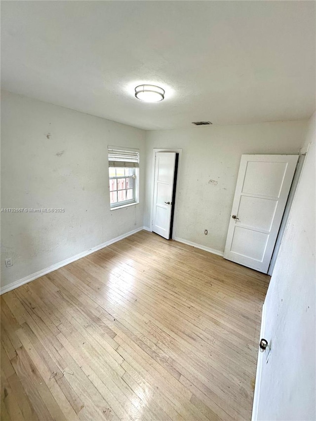 unfurnished bedroom featuring baseboards, visible vents, and light wood finished floors