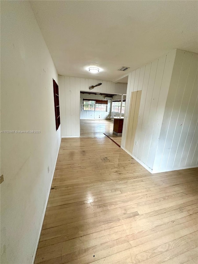 hall featuring visible vents, light wood-style flooring, and baseboards