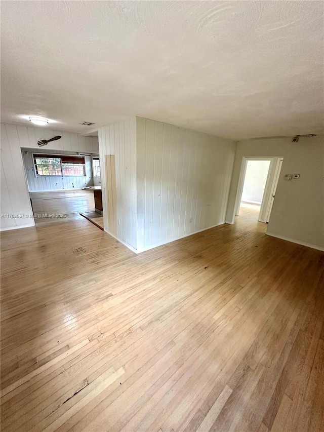 unfurnished room featuring light wood-type flooring, visible vents, and a textured ceiling